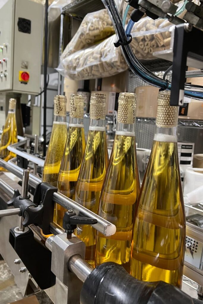 Ligne de production automatisée avec bouteilles de vin blanc en cours de bouchonnage et conditionnement