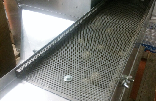 Tamis industriel en inox avec grille perforée pour le tri et le conditionnement de produits alimentaires